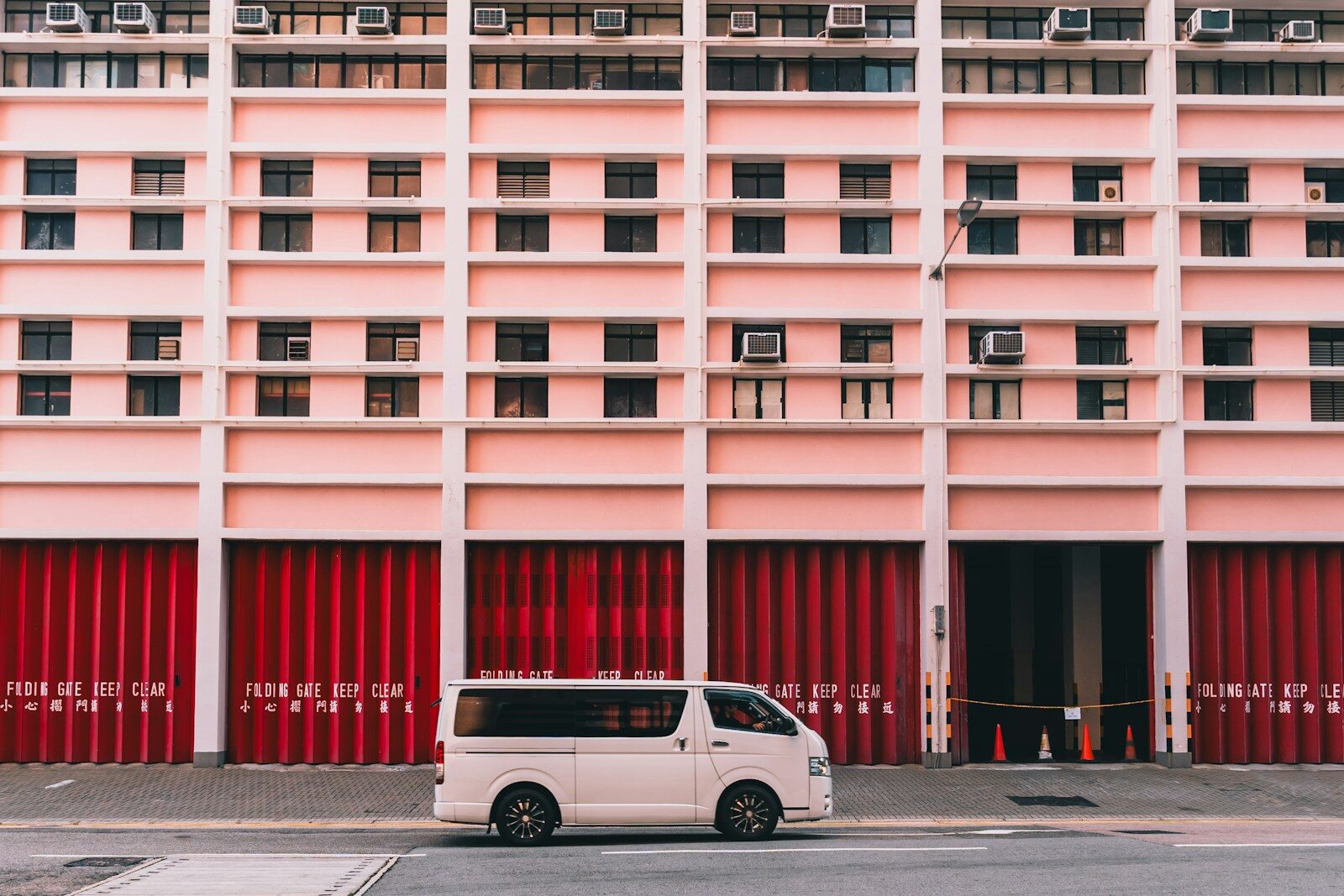 White van parked in front of a pink building.